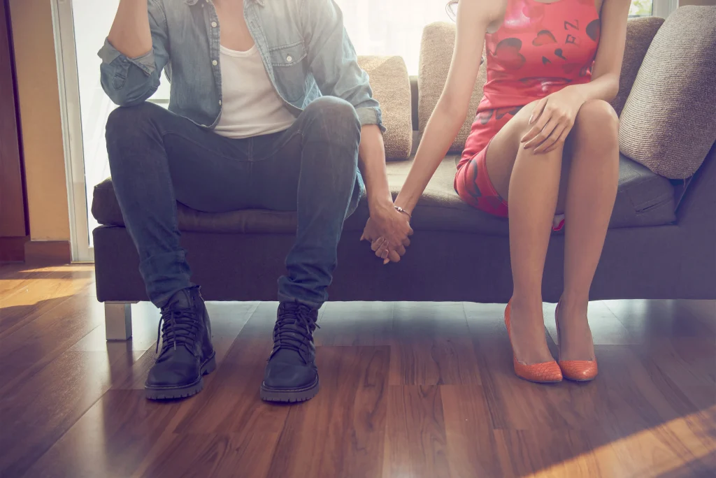 A couple sitting on a sofa holding hands
