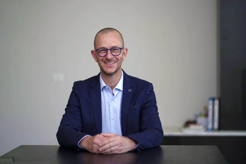 Marc Wiesner, Certified Couples Master Coach, smiling at his desk in a navy blazer